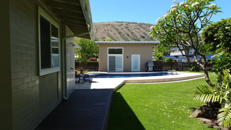 Detached backyard building beside a lawn and pool