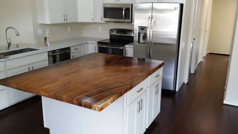 Kitchen island with a richly figured solid wood top, white cabinetry and stainless appliances
