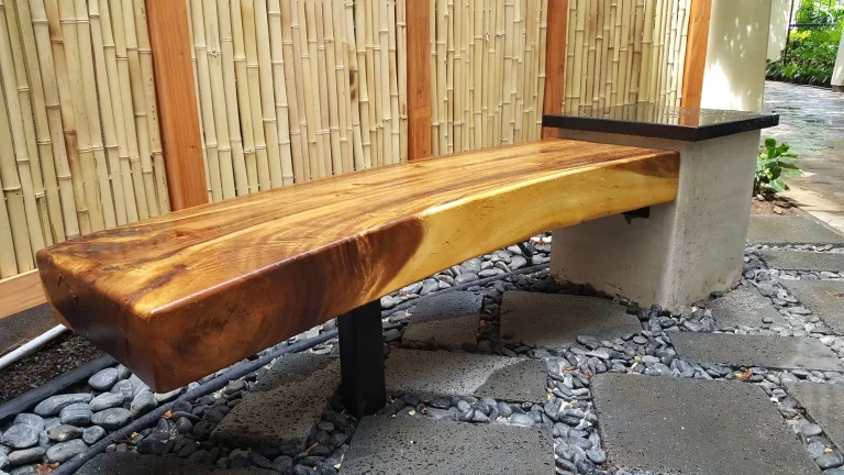 Live-edge wood bench on a concrete base beside a bamboo fence