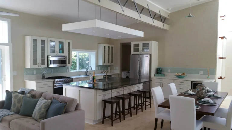 Open kitchen, dining and living area with white cabinetry, dark counters and a seating island